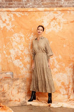 Load image into Gallery viewer, Image shows a woman wearing the CRUSHED SILK MAXI SKIRT-from Kamare brand in KHAKI  Creativity designed with gorgeous features you will be sure to turn heads when you head out in this masterpiece. Its midi length, has a full skirt is lined and made of 100% crushed silk
