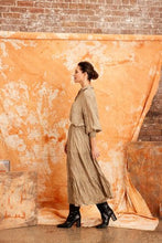 Load image into Gallery viewer, Image shows a woman wearing the CRUSHED SILK MAXI SKIRT-from Kamare brand in KHAKI  Creativity designed with gorgeous features you will be sure to turn heads when you head out in this masterpiece. Its midi length, has a full skirt is lined and made of 100% crushed silk
