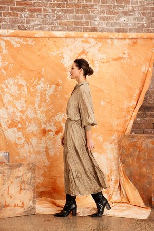 Image shows a woman wearing the CRUSHED SILK MAXI SKIRT-from Kamare brand in KHAKI  Creativity designed with gorgeous features you will be sure to turn heads when you head out in this masterpiece. Its midi length, has a full skirt is lined and made of 100% crushed silk